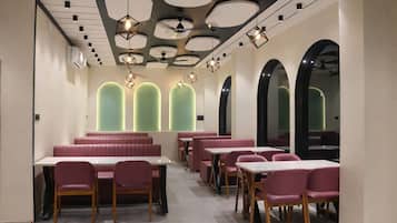 Een modern restaurantinterieur met zitjes, tafels en een uniek plafondontwerp.