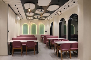 A modern restaurant interior with booths, tables, and a unique ceiling design.