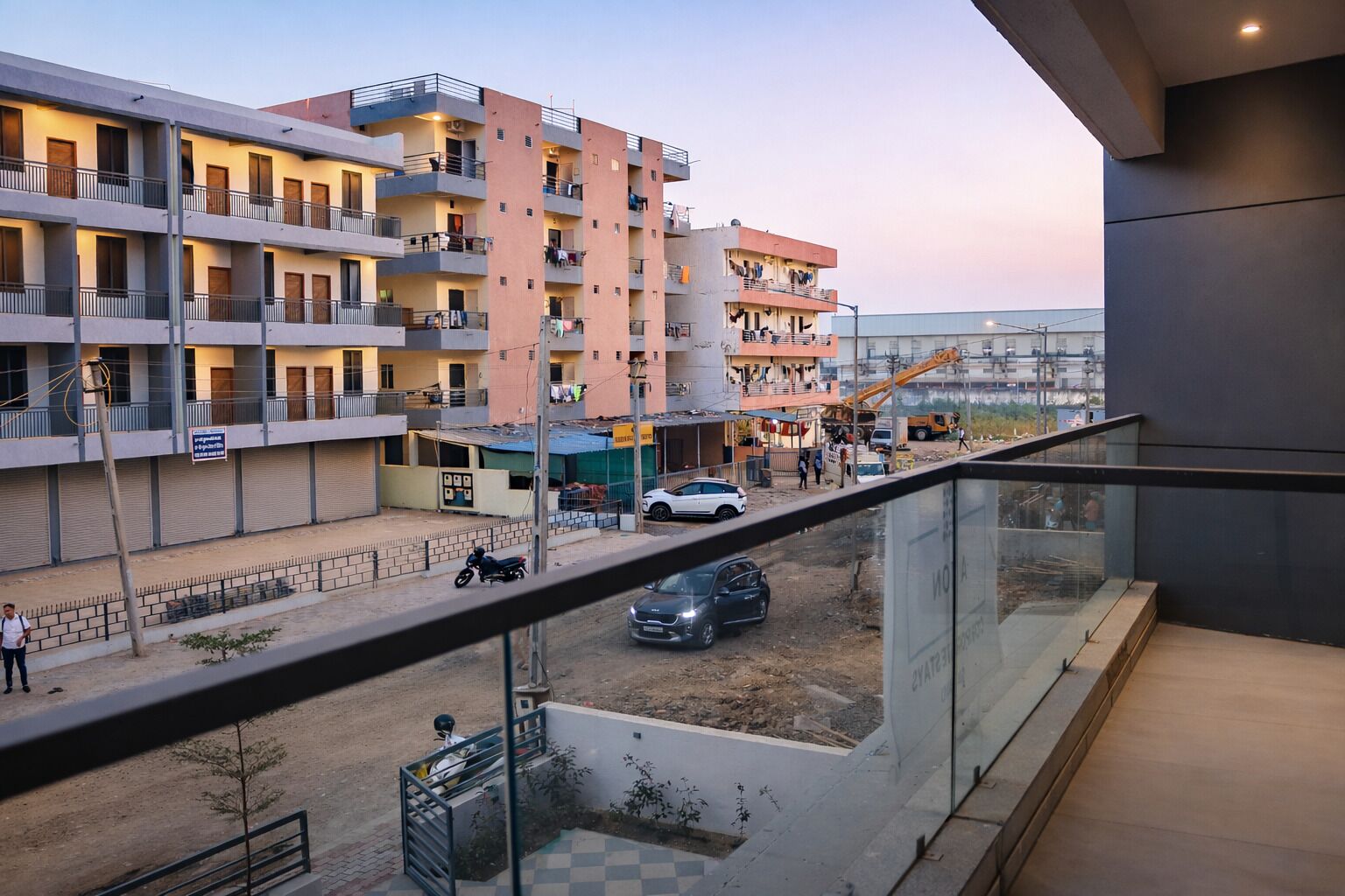Een meerlaags woongebouw met balkons, een bouwplaats voorgronds en een heldere lucht.