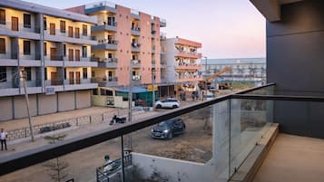 Een meerlaags woongebouw met balkons, een bouwplaats voorgronds en een heldere lucht.