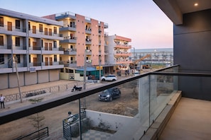 Un edificio residencial de varios pisos con balcones, una obra en construcción en primer plano y un cielo despejado.