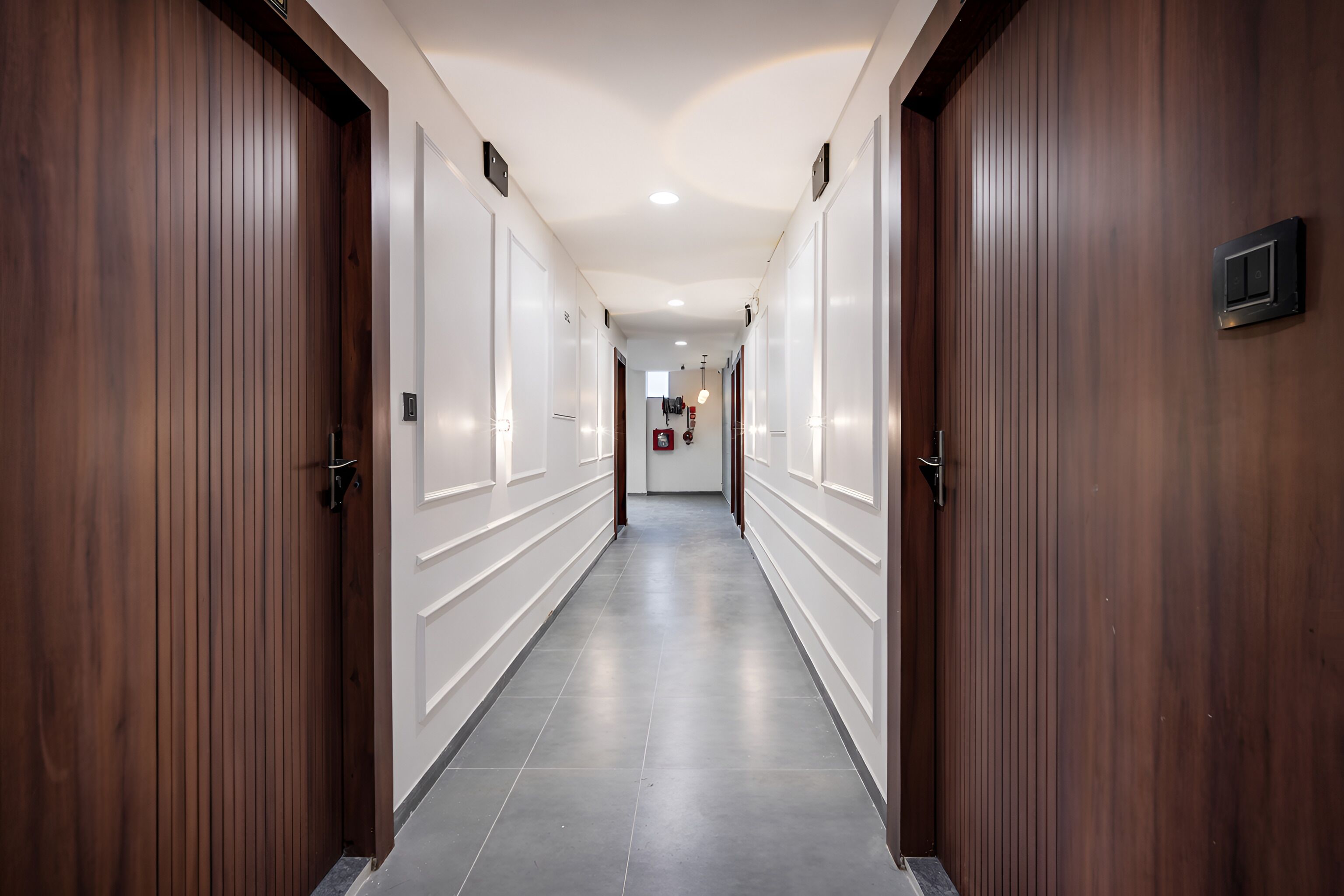 A hotel hallway with wooden doors, a tiled floor, and a ceiling light.