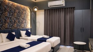 A hotel room with two beds, a small table, and an air conditioning unit. - Axon Business Hotel Sanand Ahmedabad (Ahmedabad)