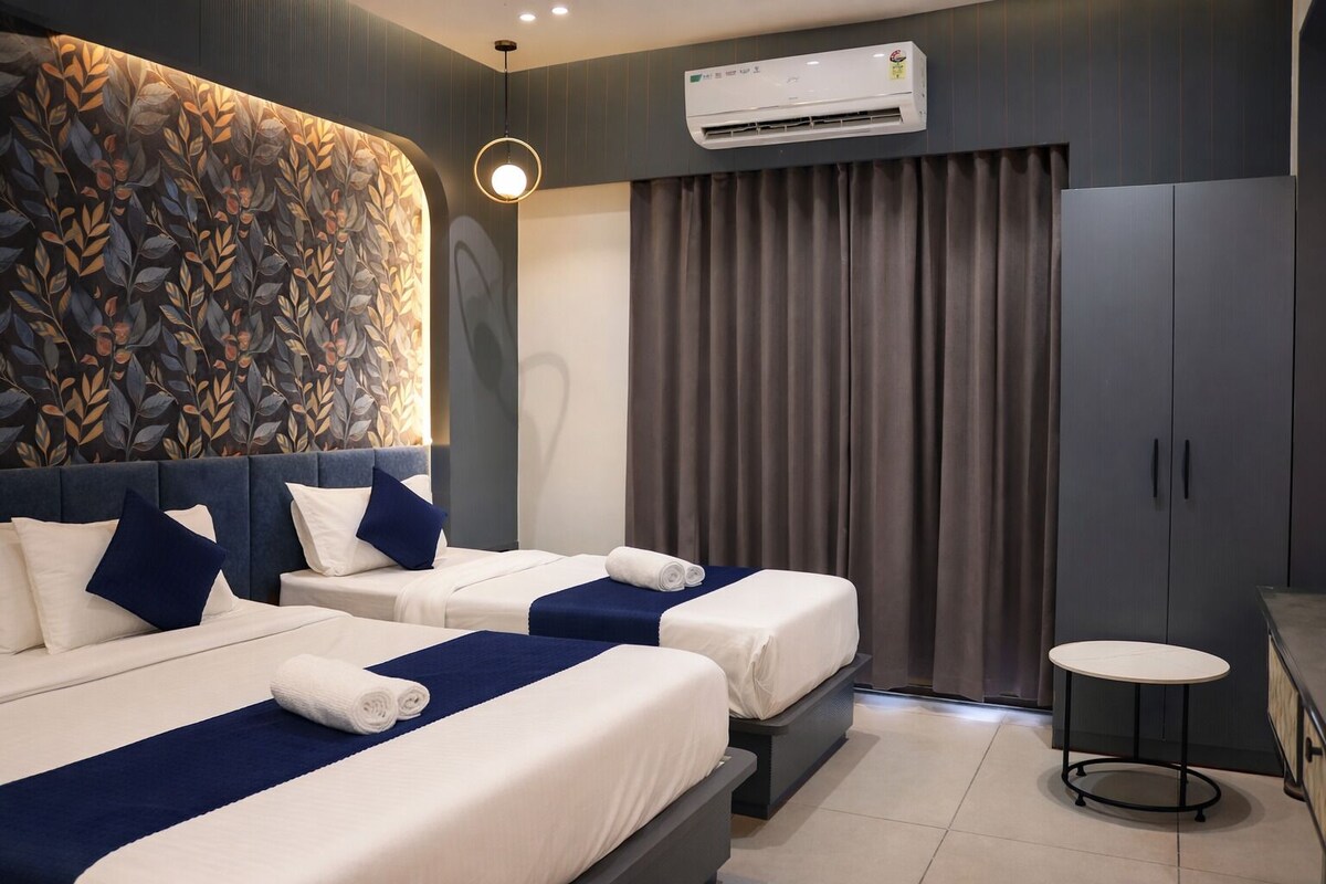 Una habitación de hotel con dos camas, una mesita y un equipo de aire acondicionado.