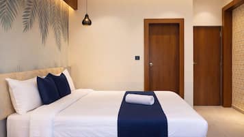 Een hotelkamer met een bed, nachtkastje, een wandlamp en een deur.