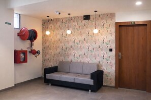 Una habitación con un sofá, un extintor, una manguera contra incendios y una puerta con el número 201.