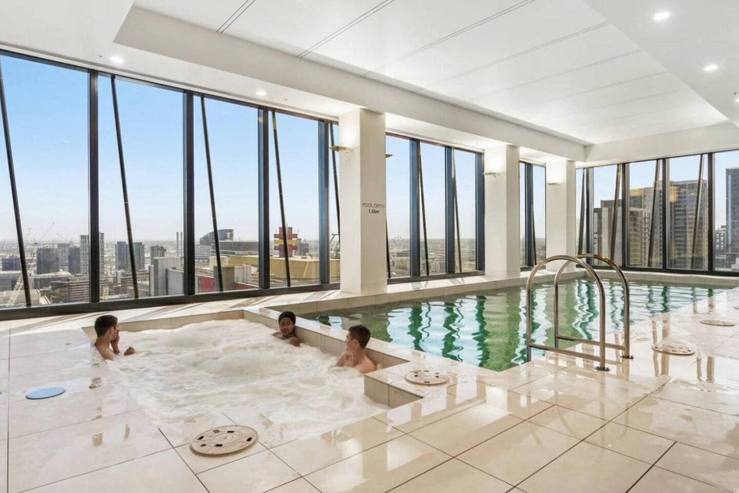 A modern indoor swimming pool with clear views of a cityscape through large windows.