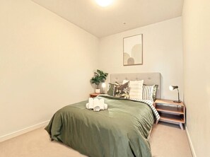 Ein Schlafzimmer mit einem Bett, einem Nachttisch, einer Lampe und einem Wandbild.