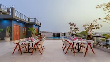 Una terrazza sul tetto con piscina, zona pranzo e vista sulla città.