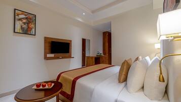 Ein Hotelzimmer mit Bett, Nachttisch und an der Wand befestigtem Fernseher.