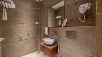 A modern bathroom with a large mirror, a white sink, and a shower area.