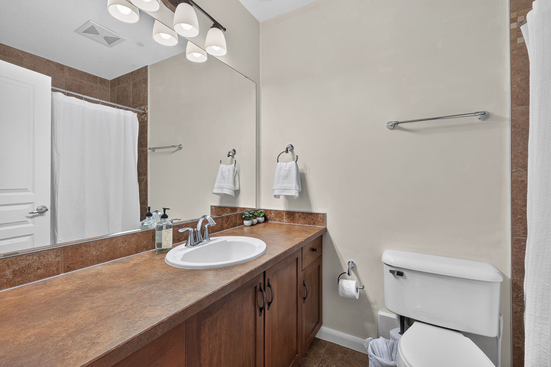 A bathroom with a sink, mirror, towel rack, and toilet.