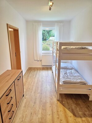 Ein Zimmer mit einem Etagenbett, einem Holzkapfen und einem Fenster mit Vorhängen.