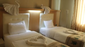 Two single beds with white linens, a wooden headboard, and a wall-mounted telephone. - GRAND ALİN HOTEL (Turhal)