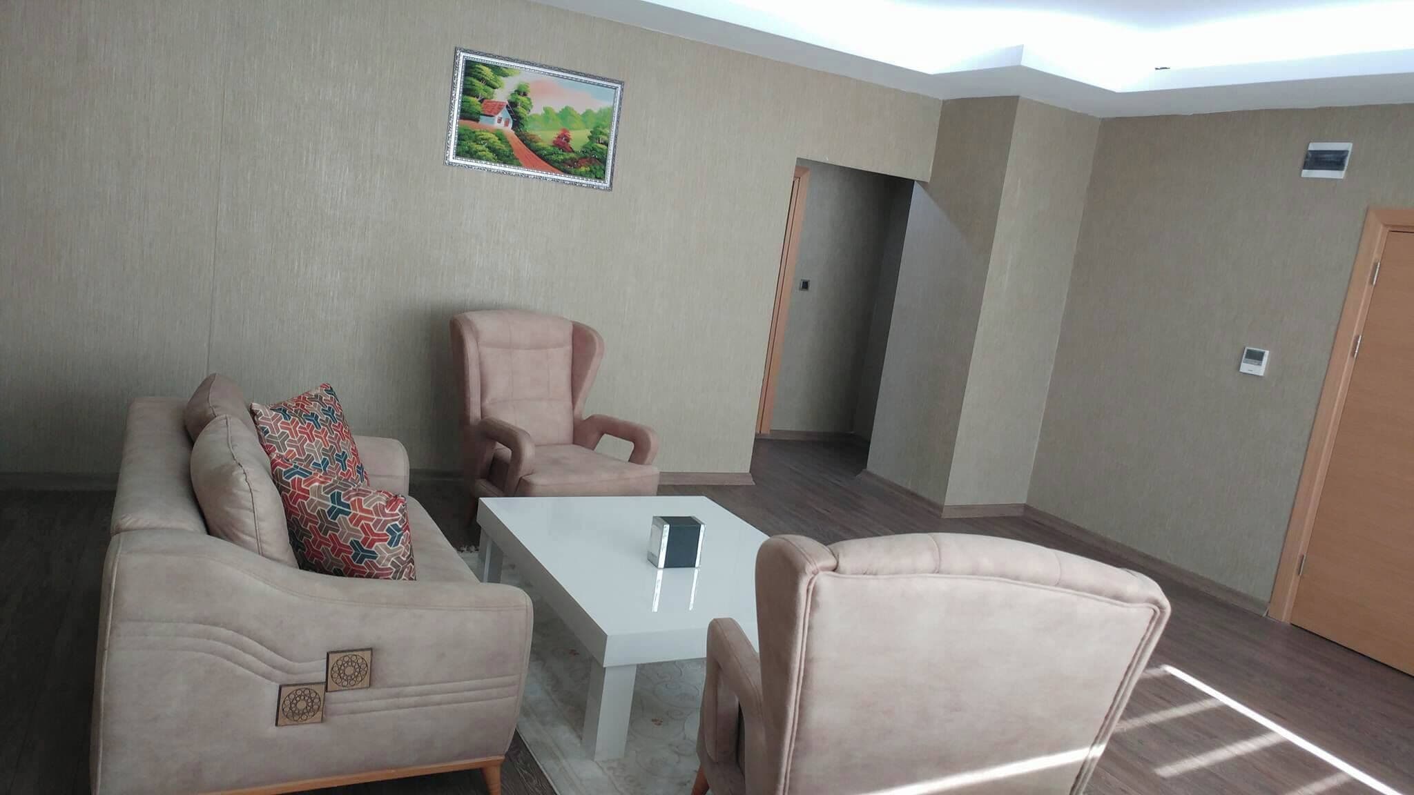 Ein Zimmer mit einem beigen Sofa, einem passenden Sessel, einem kleinen Tisch und einem Bild an der Wand.