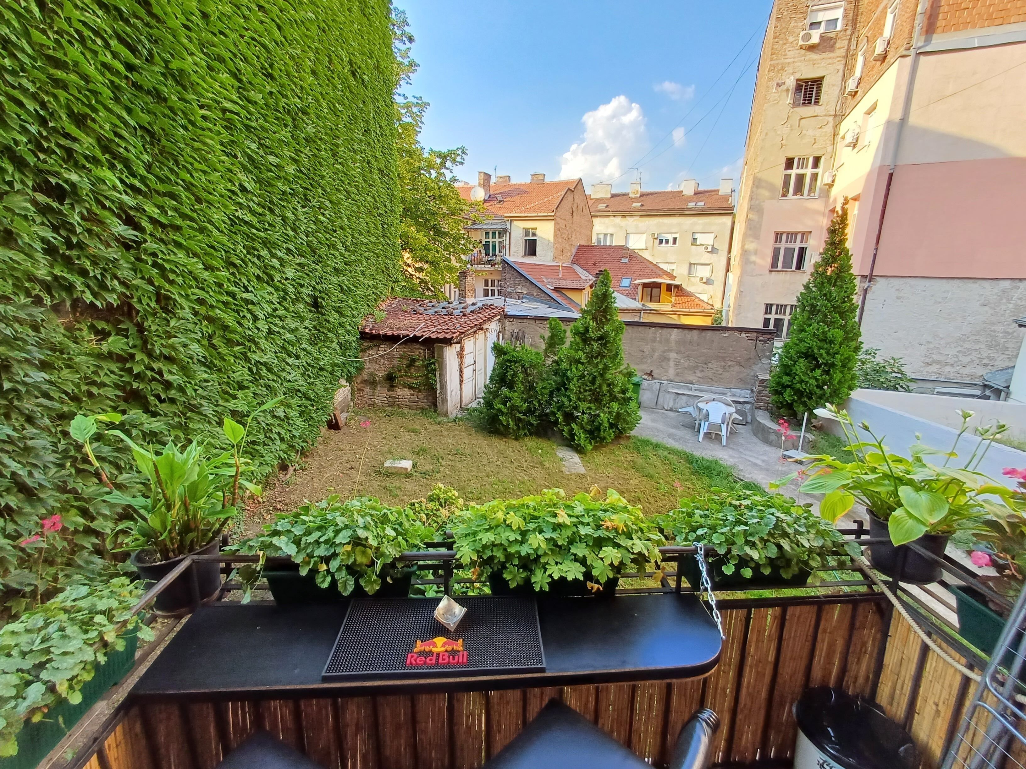 A balcony with a table, chairs, and potted plants.
