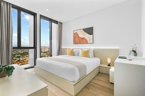 A modern hotel room with a large bed, a desk, and a view of a cityscape through large windows. - Sorvi by Kozystay - Cilandak (South Jakarta)