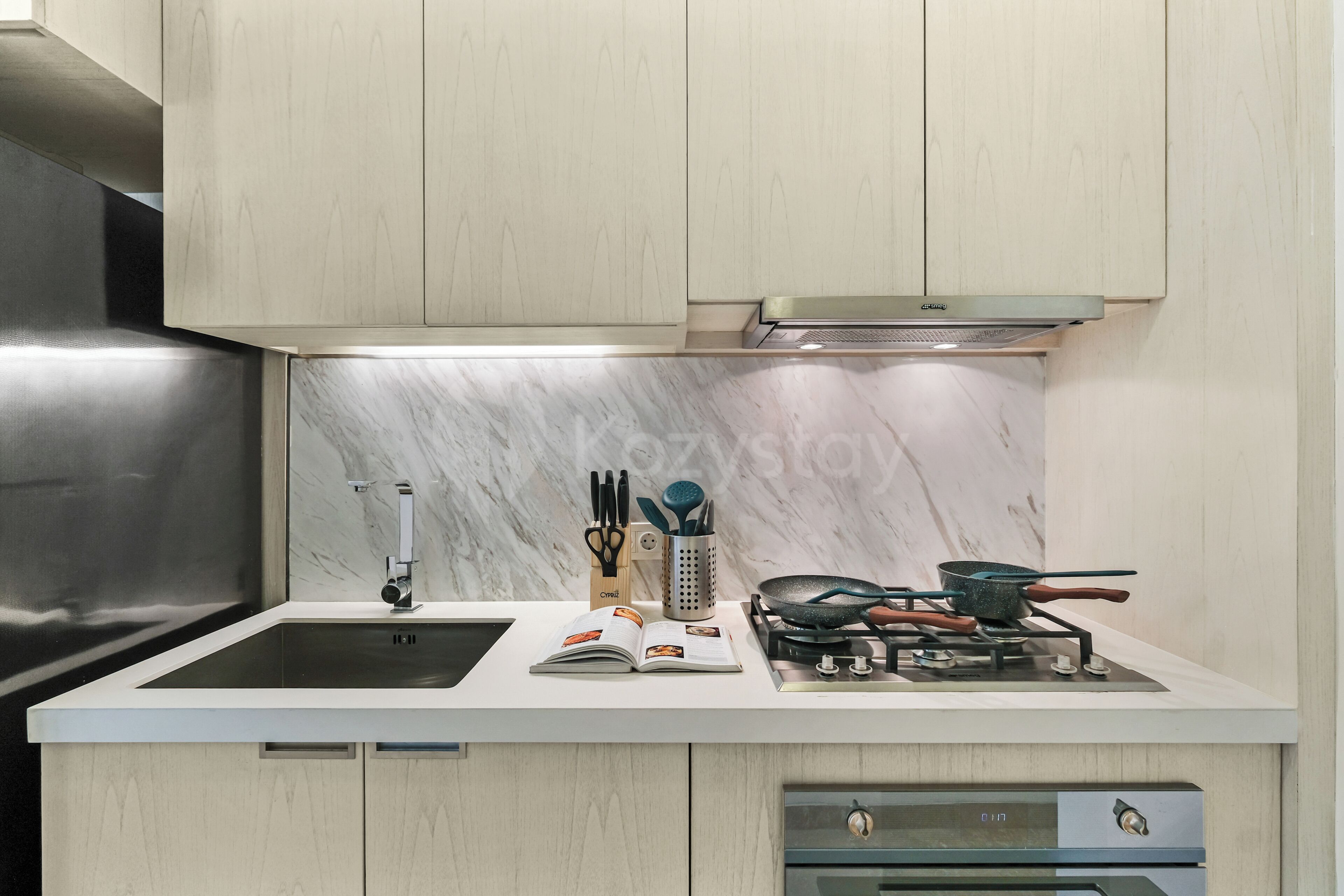 A modern kitchen with a stainless steel sink, a gas stove, and a built-in oven.