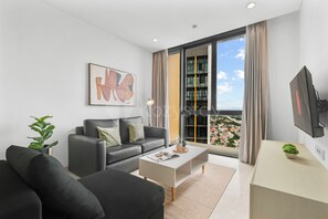 A modern living room with a sofa, coffee table, and a TV. - Sorvi by Kozystay - Cilandak (South Jakarta)