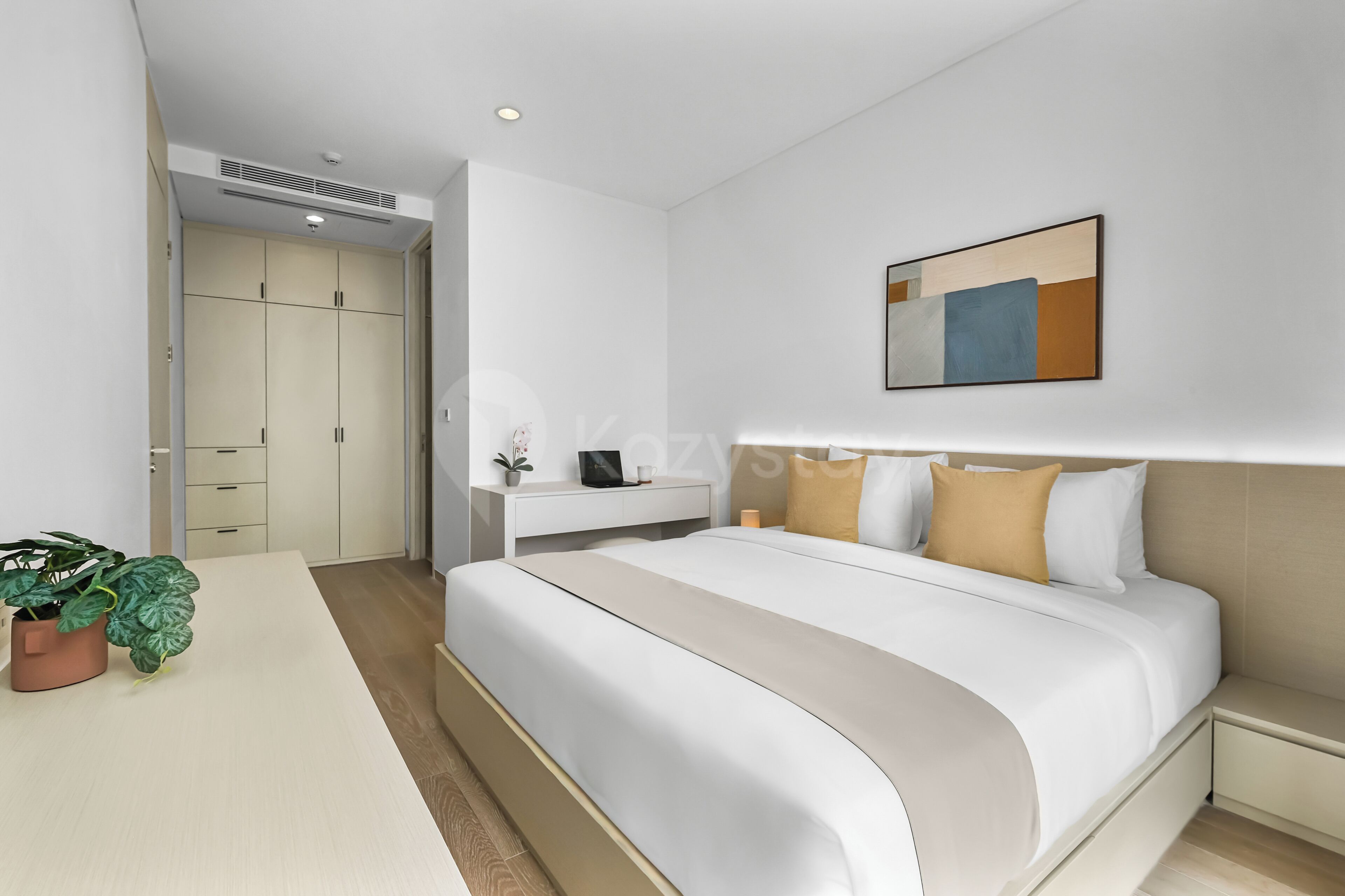 A modern bedroom with a bed, bedside table, and a painting on the wall.