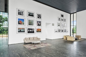 A spacious gallery with a modern interior, featuring a sofa and a coffee table, and walls adorned with framed photographs. - Sorvi by Kozystay - Cilandak (South Jakarta)