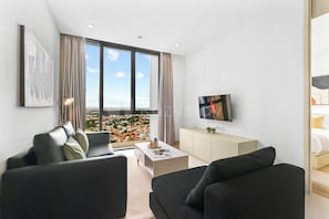 A modern living room with a sofa, a coffee table, and a TV. - Sorvi by Kozystay - Cilandak (South Jakarta)