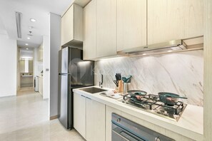 A modern kitchen with a built-in refrigerator, a gas stove, and a marble backsplash. - Sorvi by Kozystay - Cilandak (South Jakarta)