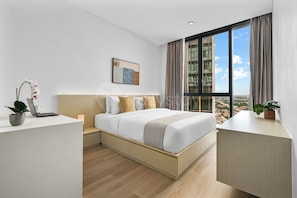 A modern hotel room with a large bed, a desk, and a view of the cityscape. - Sorvi by Kozystay - Cilandak (South Jakarta)