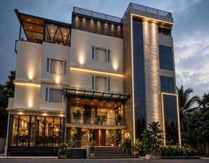 A multi-story hotel with a modern design, featuring balconies, large windows, and a well-lit entrance.