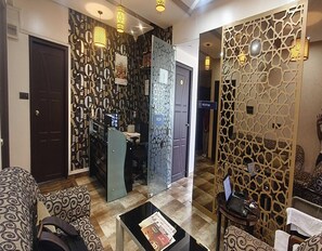 Un vestíbulo de hotel con paredes estampadas, una recepción y un área de estar con sofás decorados.