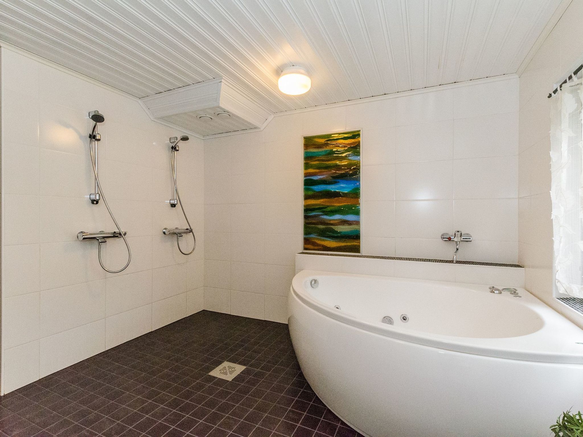 Ein modernes Badezimmer mit freistehender Badewanne, einer Dusche inklusive Handbrause und einem wandmontierten WC.