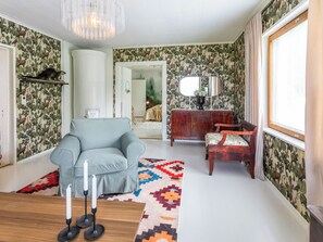 A living room with a blue sofa, a patterned rug, a wooden coffee table, and a mirror on a wooden cabinet.