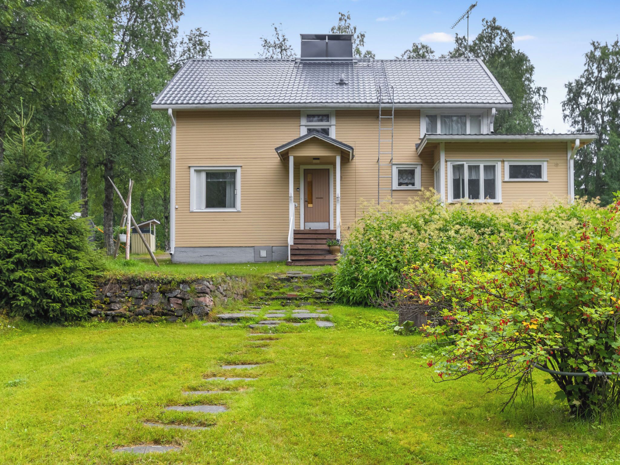Ett tvåvåningshus med en veranda på framsidan, en stenlagd gång som leder till entrén och en välskött gräsmatta.
