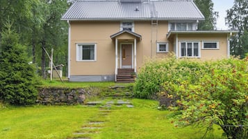 Ett tvåvåningshus med en veranda på framsidan, en stenlagd gång som leder till entrén och en välskött gräsmatta.