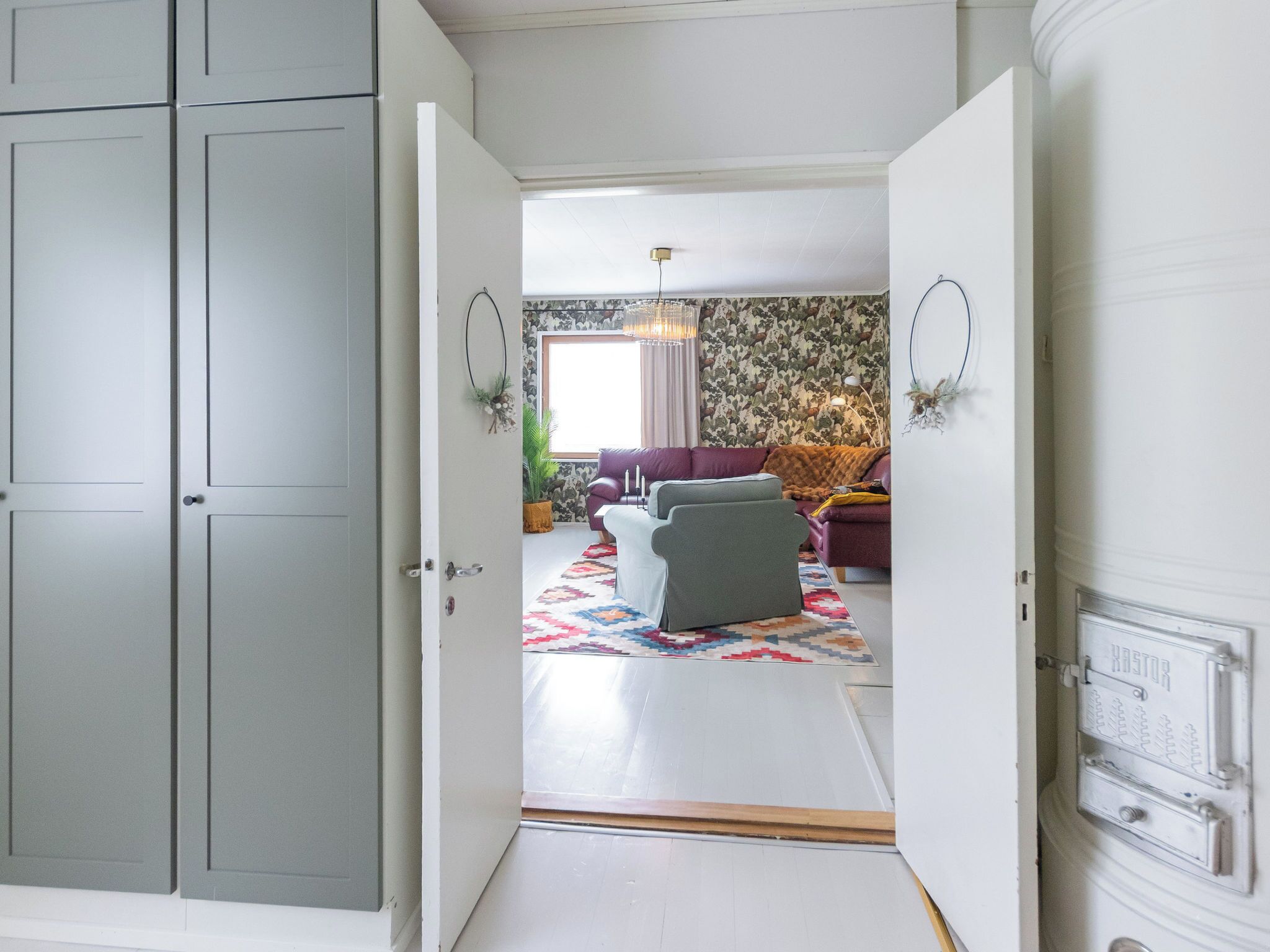 An open doorway leading to a living room with a patterned wallpaper, a sofa, and a rug.