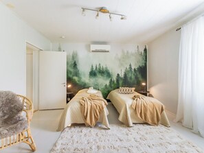 A bedroom with two beds, a large forest mural on the wall, an air conditioning unit, and a fluffy chair. - Vacation home Alpola by Interhome (Suomussalmi)