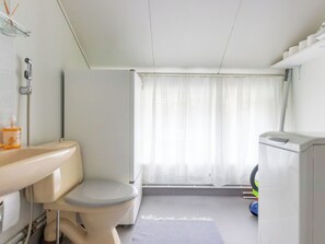 A bathroom with a toilet, sink, shower, and a window with curtains. - Vacation home Alpola by Interhome (Suomussalmi)