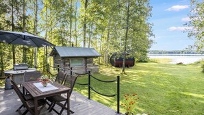 Une terrasse en bois avec une table et des chaises, un barbecue et une structure ressemblant à un chalet.