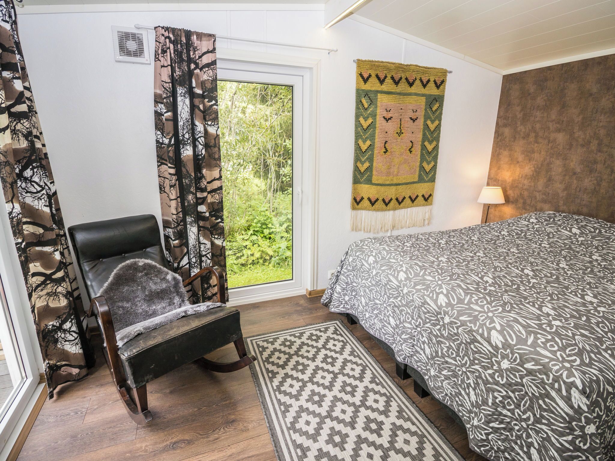 Une chambre à coucher avec un lit, une chaise, un tapis à motifs et une tapisserie.