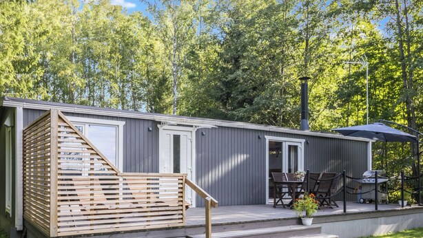 Un bâtiment compact, de plain-pied, doté d’une terrasse en bois et d’un petit espace extérieur aménagé pour s’asseoir.