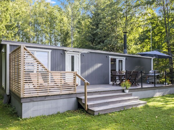 Un edificio bajo y compacto con terraza de madera y un pequeño espacio exterior para sentarse.