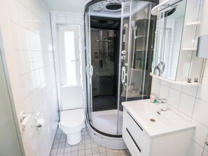 Un baño moderno con inodoro, cabina de ducha y lavamanos con espejo.