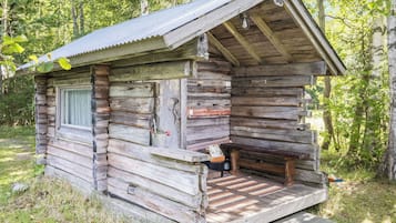 A rustic cabin with a porch, a window, and a door.