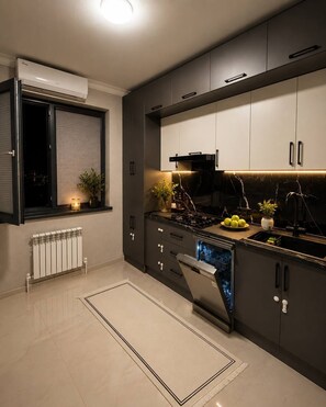 Eine moderne Küche mit eingebautem Geschirrspüler, Herd und einem Fenster mit Jalousien.