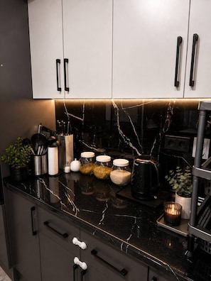 Eine moderne Küche mit schwarzen Marmorarbeitsplatten, Edelstahlgeräten und einem minimalistischen Design.