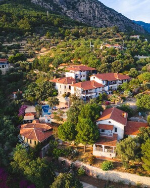 Quartiere residenziale con case dai tetti rossi, immerso nel verde con montagne sullo sfondo.