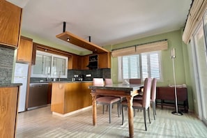 A modern kitchen with wooden cabinets, a granite countertop, and a dining area with a marble table and chairs. - Spacious Entire Floor Penthouse 200m To The Beach (Limassol)