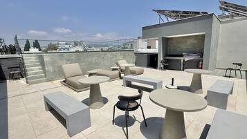 A rooftop terrace with outdoor seating, a barbecue area, and solar panels.