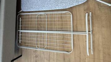 A room with a wooden floor, a metal drying rack, and a white wall.