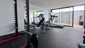 Academia com equipamentos de ginástica, suporte para pesos e esteira.